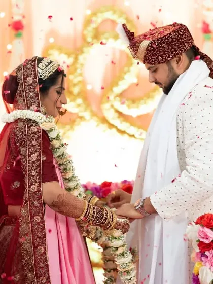 The couple holds hands during a ritual, with flower petals showering down on them.