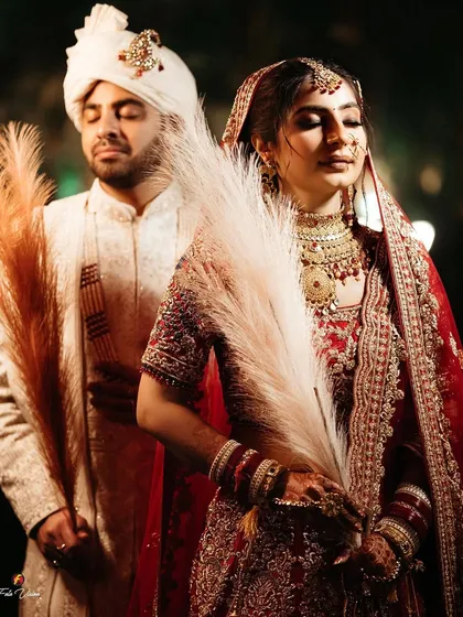An artistic and serene portrait of the couple, their eyes closed, holding delicate pampas grass.