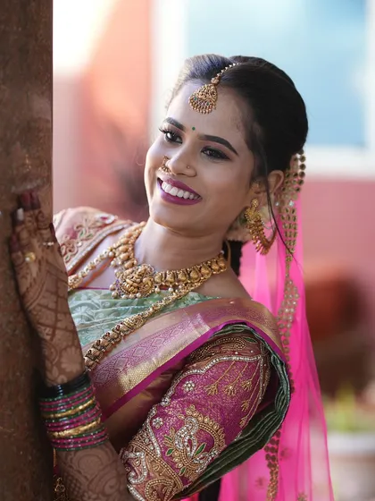 A classic bridal portrait of a smiling South Indian bride. I use natural light to highlight the intricate details of the wedding attire, from the silk saree to the temple jewelry.