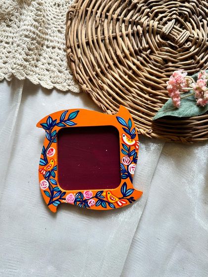 An orange photo frame magnet with a beautiful blue and pink floral vine design.