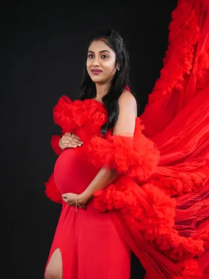 A side profile showcasing the flowing train of our red ruffled gown against a black backdrop, highlighting its dramatic silhouette.