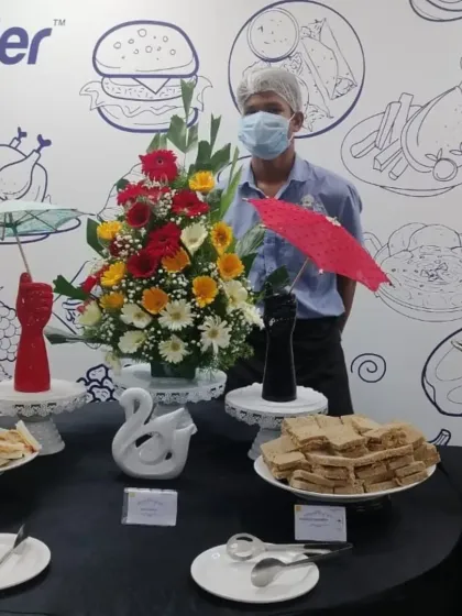 A snapshot of our snack counter at a corporate office. We provide a variety of light eats including sandwiches and Indian sweets, presented with beautiful floral arrangements and decorative touches.