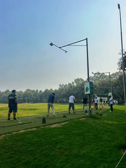 A full driving range on a Sunday, with golfers of all ages enjoying the beautiful weather.