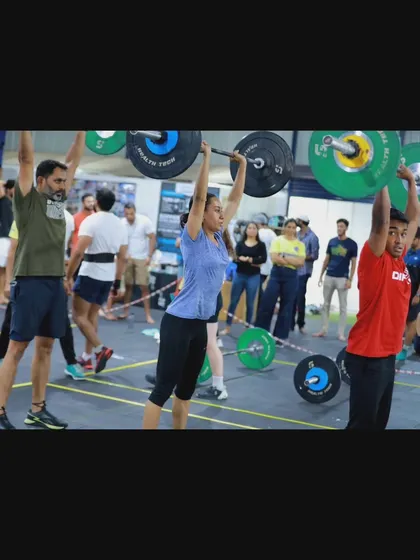 A female athlete completes a powerful push jerk overhead, demonstrating the strength and technique honed in our daily training sessions.