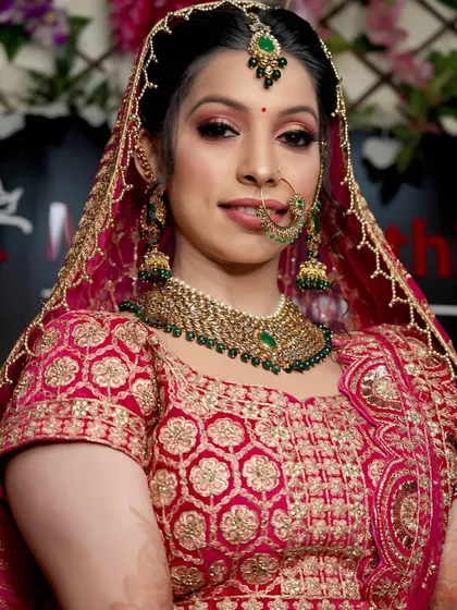 A simple, elegant headshot of the bride. This photo beautifully captures her final makeup look and the intricate embroidery of her red and pink lehenga.