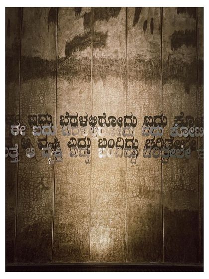 Detail of the Kannada script on the concrete wall, a tribute to the cultural context of the memorial. The texture of the wall catches the light, adding depth and character.