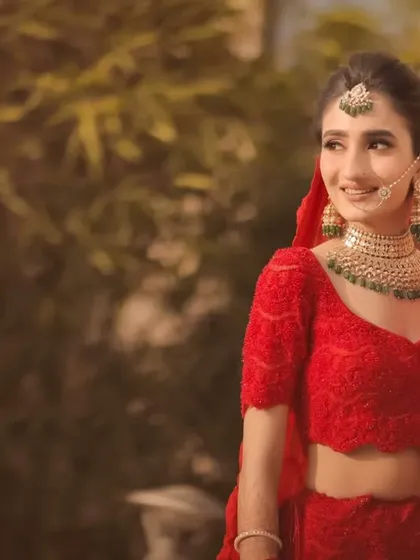 A sun kissed outdoor bridal portrait. The soft, natural light gives the bride a beautiful glow, highlighting her features and her stunning red lehenga.