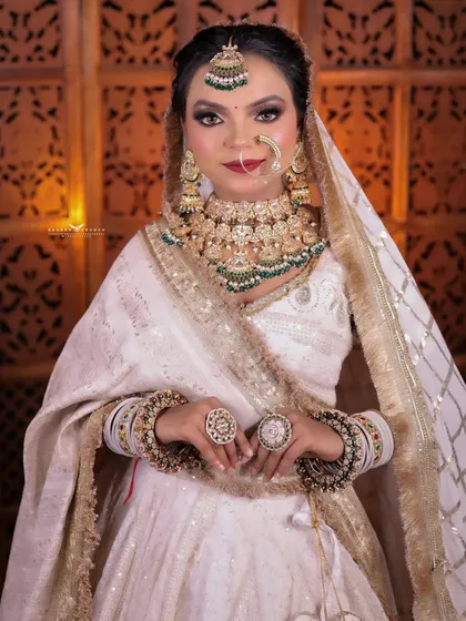 A classic portrait of the bride with her hands clasped, looking elegant in her white and gold outfit.