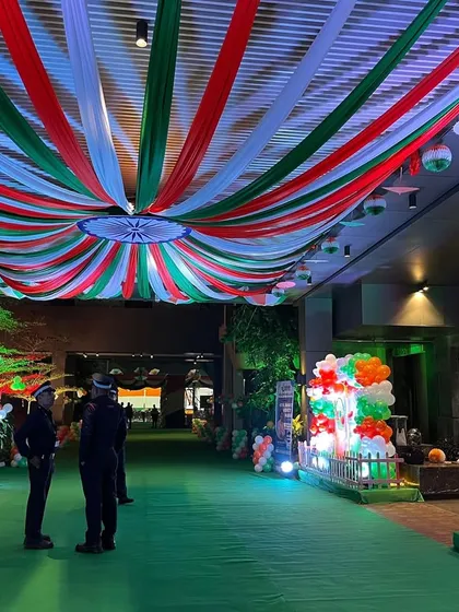 A grand entrance for a Republic Day event, featuring a long green carpet walkway and an expansive tri-color ceiling canopy. This design creates an immersive and patriotic experience for guests from the moment they arrive.