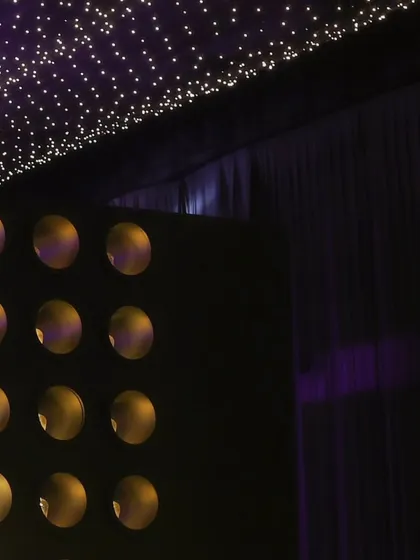 The contrast of the dark draped walls against the twinkling fairy light ceiling, a signature element of our high-end party designs.