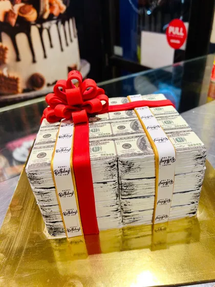 A birthday cake that looks like a million bucks. This is a stack of 100-dollar bills, complete with a red ribbon and bow, all handcrafted from cake and edible paper.