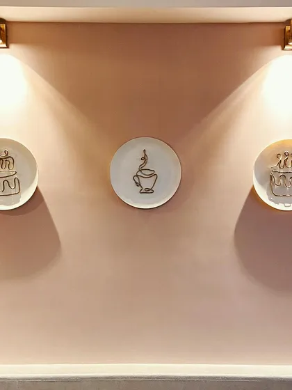 This installation was designed for a cafe wall, featuring minimal wire sculptures of a cake and coffee cup mounted on plates. The simple gold wire against the plain plates creates an elegant and modern look, perfectly complementing the cafe's aesthetic.