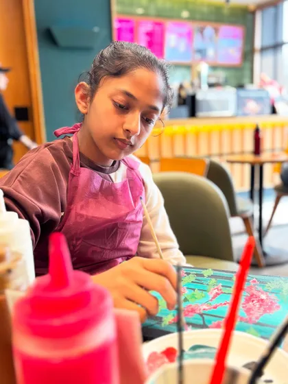 A young painter completely absorbed in her work, surrounded by colors and coffee cups. This is the perfect picture of a creative Sunday.