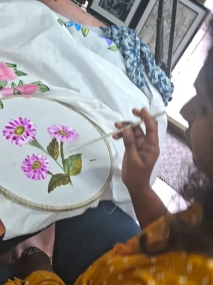 We love seeing our students get lost in the creative process. This is a quiet moment from a fabric painting session, focusing on adding delicate details to a floral design. No experience is needed, just a willingness to try.