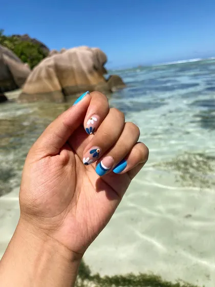 Vacation nails in their natural habitat. This client is enjoying the Seychelles with her custom blue and white floral nail art that perfectly matches the beachy vibe.