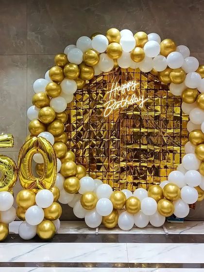 A classic and elegant 50th birthday or anniversary setup, featuring a gold and white balloon ring with a sequin backdrop.