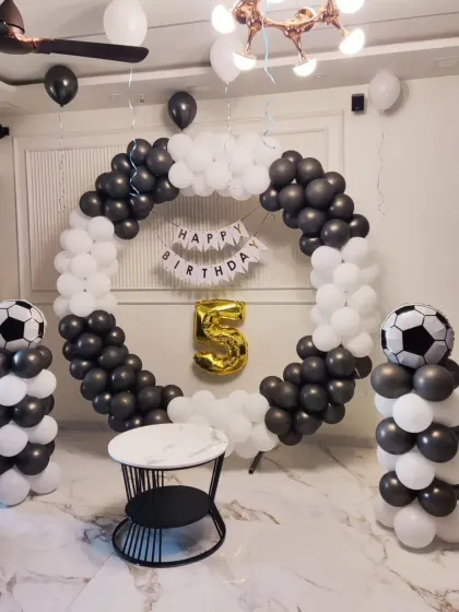 A football-themed 5th birthday with a black and white balloon ring and football-print balloons.