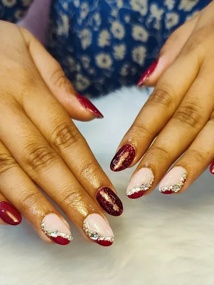 Glitter makes everything better, especially red nails. This festive set features a mix of red nails and nude accent nails with a red glitter tip and crystal details.