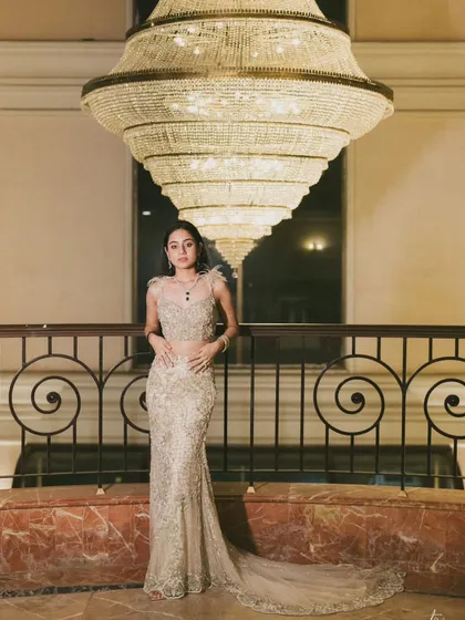 A solo portrait of the bride-to-be, Anmol, standing beneath a stunning tiered chandelier. I wanted to create an image that highlighted her grace and the exquisite detail of her gown in a grand, architectural setting.