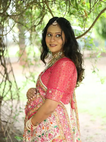 A beautiful outdoor portrait. The natural light enhances her pregnancy glow, which is complemented by the soft makeup.