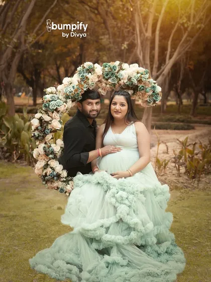 The dad-to-be joins his partner for a sweet photo by the floral arch. This showcases another beautiful option for a romantic couple's outdoor maternity session.