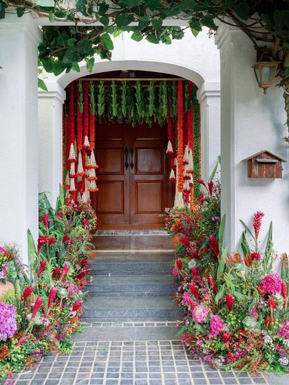 The entrance to a home transformed for a Pellikuthuru ceremony, with lush floral arrangements lining the steps.