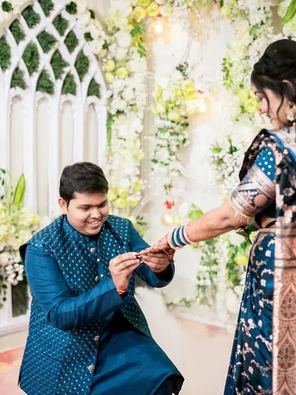 Capturing the same moment from a different perspective tells more of the story. Here, the focus shifts to the groom's happy expression as he kneels to offer the ring, showcasing the emotion and tradition of the engagement ceremony.