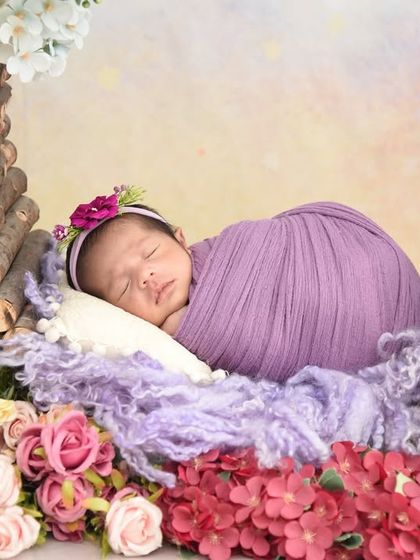 A wider view of the purple floral basket setup, surrounded by a bed of colorful flowers, creating a lovely garden scene.