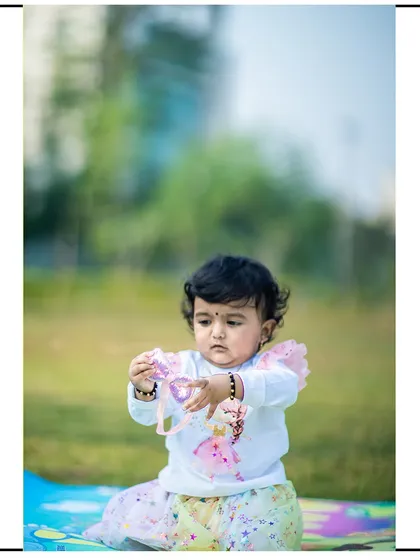 A toddler engrossed in playing with her toy during an outdoor session. These candid moments of concentration are just as precious as the smiles.