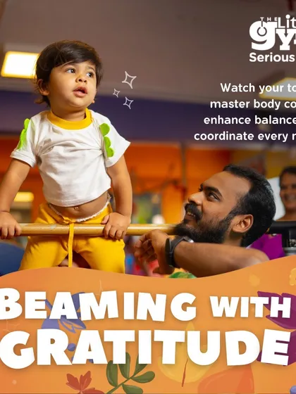 A father proudly looks on as his toddler practices balancing on a low bar. These shared moments of achievement are what make our parent-child classes so special, building both skills and memories.