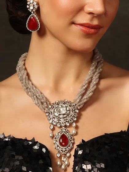 A modern classic. This necklace features a multi-strand design of grey beads with a central polki and ruby pendant, blending tradition with contemporary style.