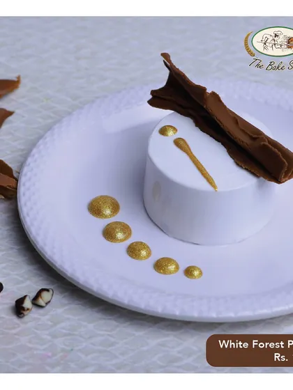 An elegant White Forest Pastry, beautifully plated with a chocolate garnish and gold dust.