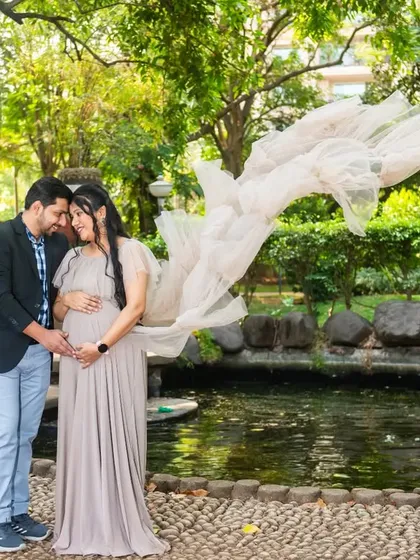 The flowing fabric of this neutral-toned gown creates a sense of movement and grace in this wide shot by a garden pond.
