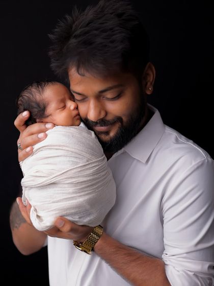 A father cradles his sleeping newborn against his chest. This tender portrait captures the feeling of protection and deep affection in the earliest days of fatherhood.