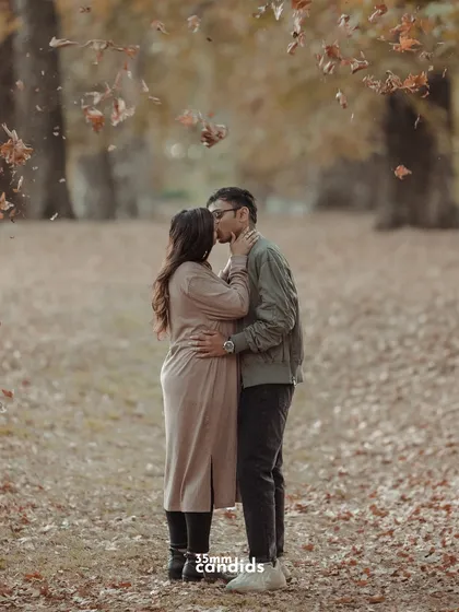 An intimate moment as the couple kisses under a shower of falling autumn leaves. A perfectly timed, romantic shot that captures the magic of the season.