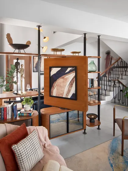 A key feature of the Raghavan Valley home is this bespoke rotating TV unit, a perfect example of flexible design. It acts as a partition between the living and dining areas, allowing for shared or separate experiences. The unit combines warm wood tones and sleek metal, integrating storage and display shelves to be both a functional and artistic centerpiece.