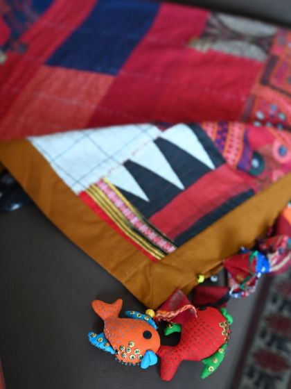 A close-up of the quilt's corner, highlighting the playful, handmade fish charms made from fabric scraps. These quirky details add a touch of fun and personality.