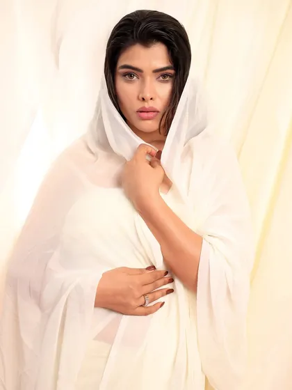 A close-up of the model draped in white, with a direct and powerful gaze that creates a timeless and classic feel.