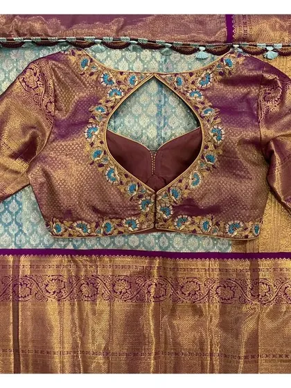This violet brocade blouse has a teardrop-shaped keyhole back, outlined with beautiful blue and gold floral embroidery.