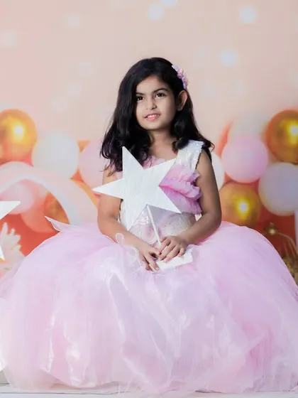 A sweet and dreamy portrait of a little princess. The soft pink tones, fluffy dress, and star props create a fairytale-like setting for a birthday or milestone shoot.