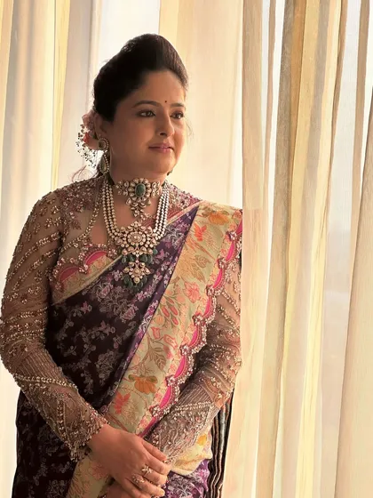 An exceptionally elegant look for a wedding guest. The makeup is subtle and refined, with a focus on flawless skin to complement her intricate designer saree and statement pearl jewelry.