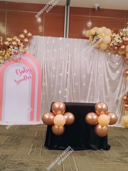 A "Baby Saadh" decoration with a modern arch backdrop and a rose gold balloon garland.