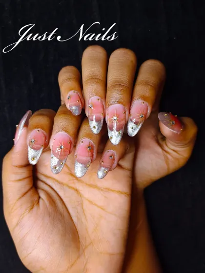 An ethereal design with a sheer pink base, silver glitter tips, and delicate star-like rhinestone and gold bead embellishments.