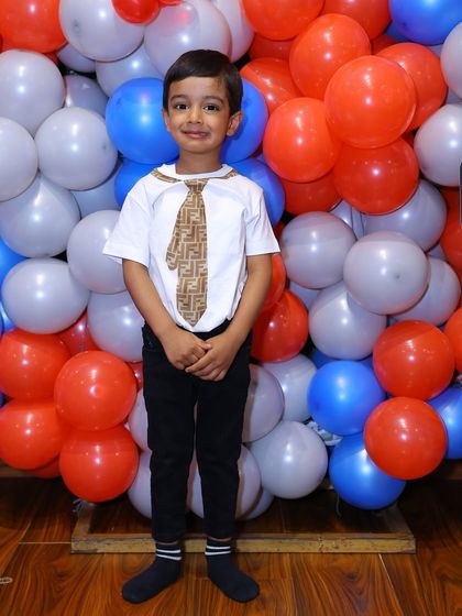 The birthday boy poses in front of a wall of red, white, and blue balloons, perfectly matching his Spider-Man and Avengers party theme.