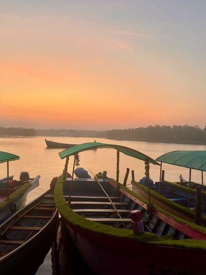 Boats waiting at the dock in Honnavar as the sun sets, painting the sky in beautiful colors.