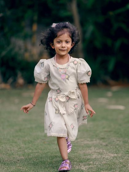 A young girl runs playfully across the grass. Capturing children in motion adds a sense of life and energy to the photo gallery.