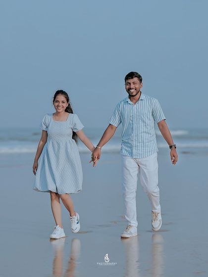 Walking towards the camera with genuine smiles. The blue and white outfits complement the sea and sky perfectly for this beach pre-wedding shoot.