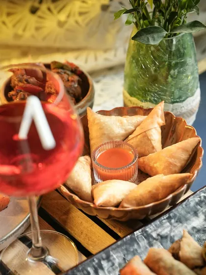 A lifestyle shot of the Chicken Irani Samosas, perfect for pairing with a refreshing drink. These are a staple for my Iftar and party menus.