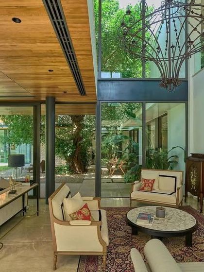 A grand, double-height living space is anchored by a fireplace and a dramatic chandelier, with views looking out into the central courtyard.