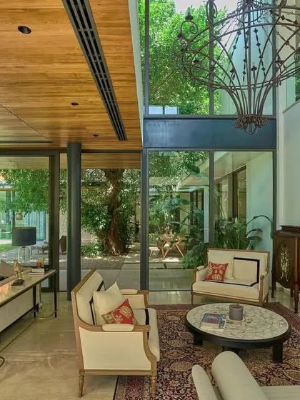 A grand, double-height living space is anchored by a fireplace and a dramatic chandelier, with views looking out into the central courtyard.